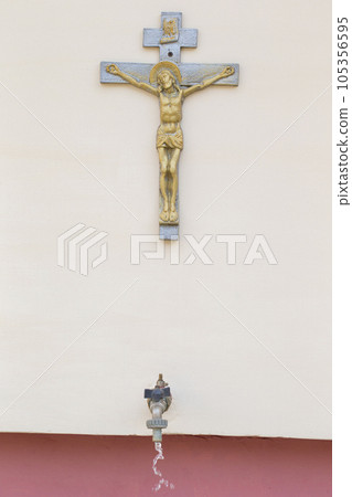 Cross with Jesus and a faucet with holy water. Religion. Cross with Jesus and a faucet with holy water. Religion. 105356595