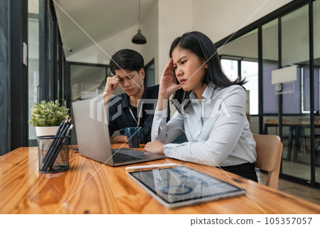 Two Asian business feeling migraine head strain. Overworked businesswoman financier while working on laptop and tablet at office Two Asian business feeling migraine head strain. Overworked businesswoman financier while working on laptop and tablet at office 105357057