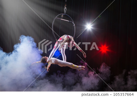 Circus actress acrobat performance. Two girls perform acrobatic elements in the air ring. 105357664