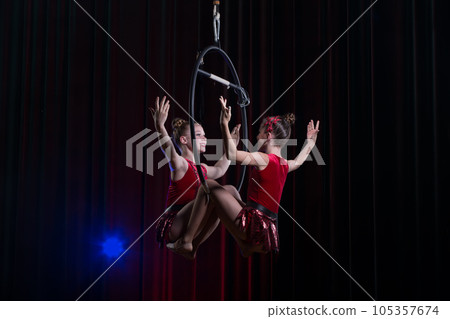 Circus actress acrobat performance. Two girls perform acrobatic elements in the air ring. Circus actress acrobat performance. Two girls perform acrobatic elements in the air ring. 105357674