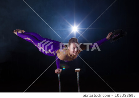 Circus actress performs the number in a beautiful smoke. Manual equilibrium on canes. Flexible girl body.Performance of an air gymnast in a circus Circus actress performs the number in a beautiful smoke. Manual equilibrium on canes. Flexible girl body.Performance of an air gymnast in a circus 105358693