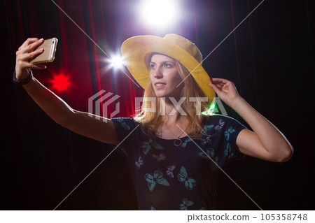 Girl in a hat makes selfie on the background of the scene; 105358748