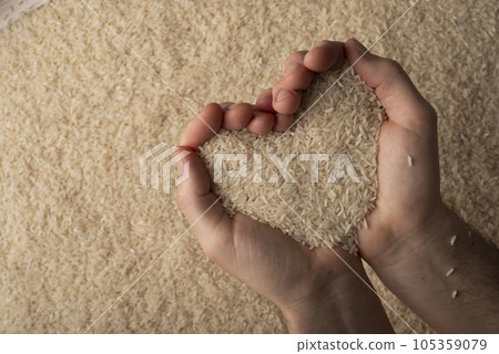 Human hands in shape of heart holding handful of rice on rice background 105359079
