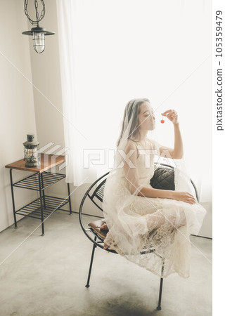 穿著白色連衣裙的年輕女子在室內拿著櫻桃 穿著白色連衣裙的年輕女子在室內拿著櫻桃 105359479