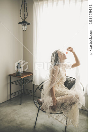 穿著白色連衣裙的年輕女子在室內拿著櫻桃 穿著白色連衣裙的年輕女子在室內拿著櫻桃 105359481