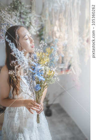 Beautiful woman in a white dress holding a bouquet of dried flowers 105360262