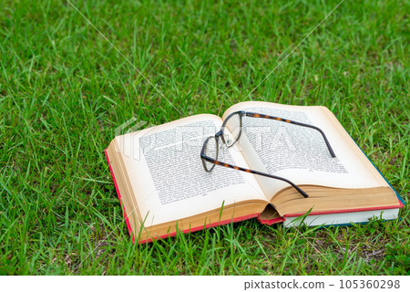Book and glasses on green grass 105360298