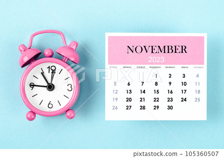 The November 2023 Monthly calendar for 2023 year with pink color alarm clock on blue background. The November 2023 Monthly calendar for 2023 year with pink color alarm clock on blue background. 105360507