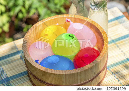 Water balloons in a wooden bucket and a cold bottle of ramune / Image of summer vacation, Showa retro, playing in the water in Japanese summer Water balloons in a wooden bucket and a cold bottle of ramune / Image of summer vacation, Showa retro, playing in the water in Japanese summer 105361299