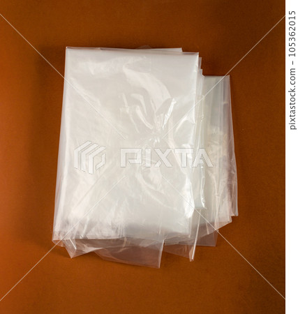 Folded White Plastic Bags on Brown Background, Crumpled Plastic Bag after Shopping, Cellophane Packaging Waste 105362015