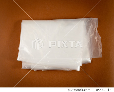 Folded White Plastic Bags on Brown Background, Crumpled Plastic Bag after Shopping, Cellophane Packaging Waste 105362018
