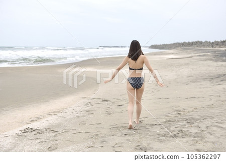 Back view of a young woman wearing a polka dot bikini on the beach Back view of a young woman wearing a polka dot bikini on the beach 105362297