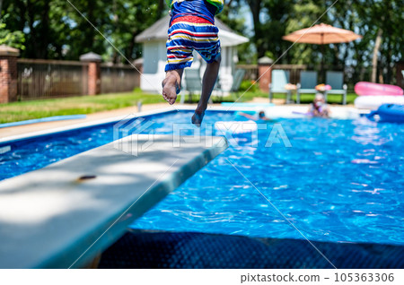 Selective focus on a swimming board as a young boy jumps into a pool.  105363306