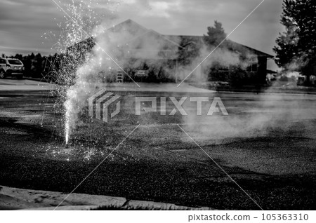 A fountain of sparks, flames, and smoke emitting from a fountain fireworks being set off in a residential neighborhood. A fountain of sparks, flames, and smoke emitting from a fountain fireworks being set off in a residential neighborhood. 105363310