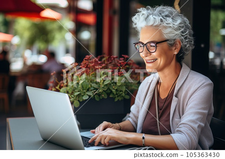 Picture of a smiley senior freelancer woman in front of laptop monitor at sidewalk cafe. 105363430