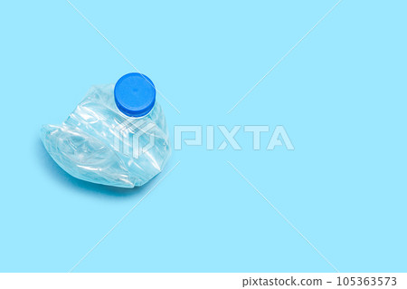 One used bottle PET plastic recycling concept. Flat plastic bottle recycling design blue background. Single crushed bottle crumpled plastic garbage PET recycling background top view 105363573