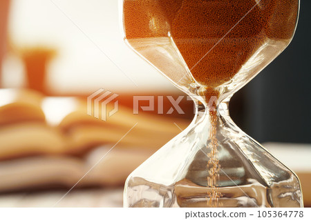 Closed up of sandglass or hourglass on background of book Closed up of sandglass or hourglass on background of book 105364778