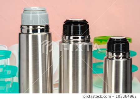 Thermos bottle against tableware in a kitchen Thermos bottle against tableware in a kitchen 105364962