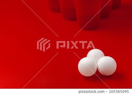 Cups and plastic ball on red background. Beer pong game Cups and plastic ball on red background. Beer pong game 105365045