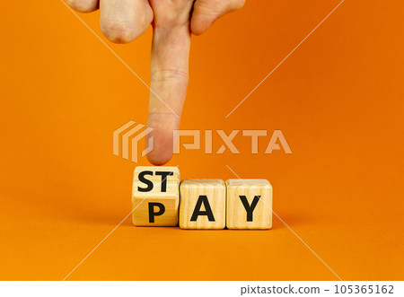 Stay and pay symbol. Businessman turns wooden cubes and changes the word Stay to Pay. Beautiful orange table orange background. Copy space. Business and stay and pay concept. Stay and pay symbol. Businessman turns wooden cubes and changes the word Stay to Pay. Beautiful orange table orange background. Copy space. Business and stay and pay concept. 105365162