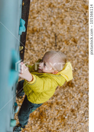 Boy At The Climbing Wall Without A Helmet, Danger At The Climbing Wall. Little Boy Climbing A Rock Wall Indoor 105366114