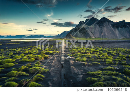 Vestrahorn mountain with green grass and dirty road on black sand beach in summer Vestrahorn mountain with green grass and dirty road on black sand beach in summer 105366248