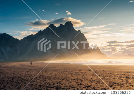 Vestrahorn mountain during sunrise and man standing on black sand beach in Stokksnes peninsula on summer at Iceland Vestrahorn mountain during sunrise and man standing on black sand beach in Stokksnes peninsula on summer at Iceland 105366255