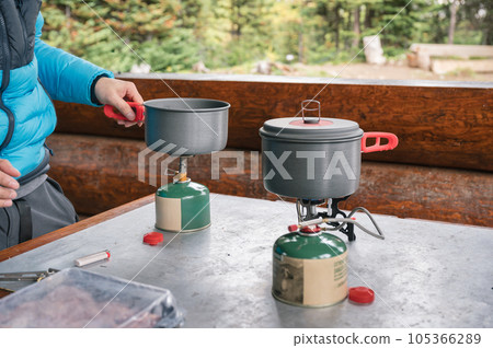 Tourist setting up pot on burner with canned gas in campground Tourist setting up pot on burner with canned gas in campground 105366289