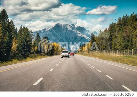 Car driving on highway to rocky mountains in autumn forest at national park Car driving on highway to rocky mountains in autumn forest at national park 105366290