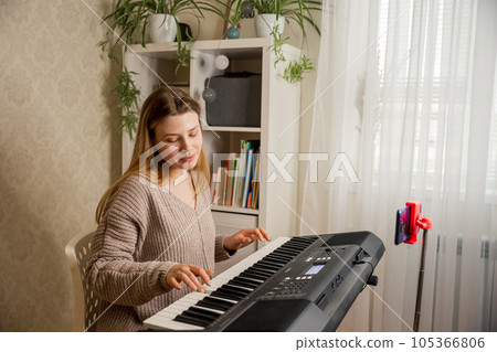 Young woman music teacher playing electric piano teaching remotely Young woman music teacher playing electric piano teaching remotely 105366806