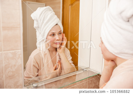 Portrait of young girl with towel on head in bathroom looks Portrait of young girl with towel on head in bathroom looks 105366882