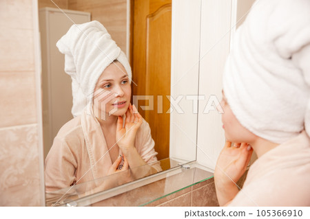 Young woman sits in the bathroom in front of the makeup mirror Young woman sits in the bathroom in front of the makeup mirror 105366910
