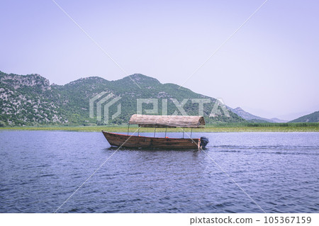 Montenegro, On a boat on waterway through green lily plants covering surface of skadar lake, a 105367159