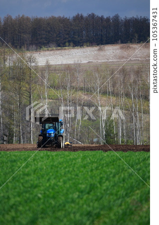 Tractor plowing a field in the spring field Tractor plowing a field in the spring field 105367431