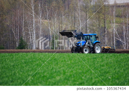 Tractor plowing a field in the spring field Tractor plowing a field in the spring field 105367434