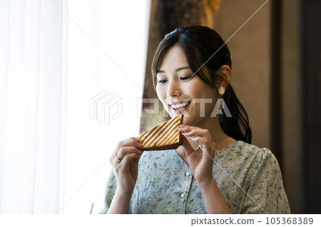 A young woman eating bread at a cafe A young woman eating bread at a cafe 105368389