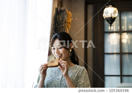 A young woman eating bread at a cafe 105368396