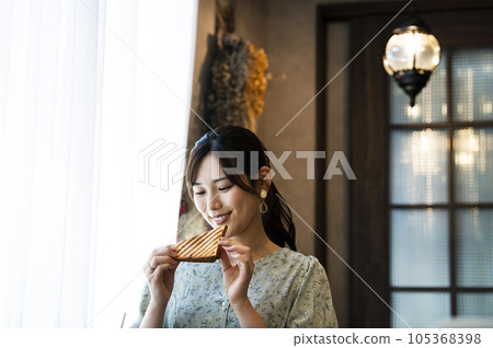 A young woman eating bread at a cafe 105368398