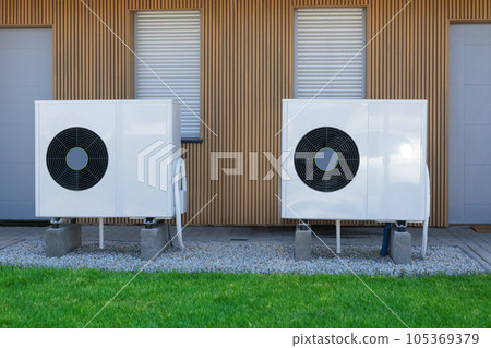High-efficiency air source heat pumps installed on the exterior of a contemporary home, utilizing green electricity for sustainable heating solutions. High-efficiency air source heat pumps installed on the exterior of a contemporary home, utilizing green electricity for sustainable heating solutions. 105369379