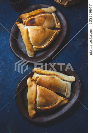 Tipical Chilean baked empanadas de pino y napolitano on clay plates with wine. Dish and drink on 18 September party Independence day Chile, blue background. 105369647