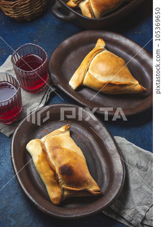 Tipical Chilean baked empanadas de pino y napolitano on clay plates with wine. Dish and drink on 18 September party Independence day Chile, blue background. 105369650