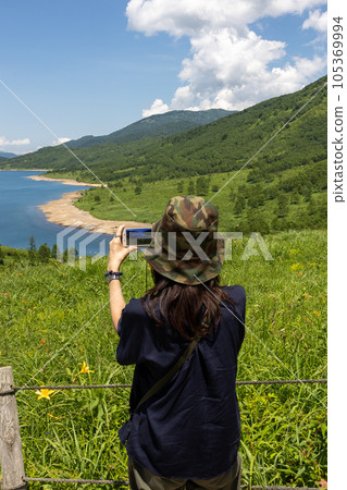 A woman taking pictures of Lake Nozori in summer from Fujimi Pass A woman taking pictures of Lake Nozori in summer from Fujimi Pass 105369994