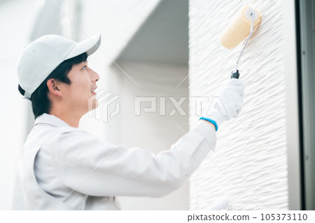 Young male contractor doing exterior wall coating 105373110