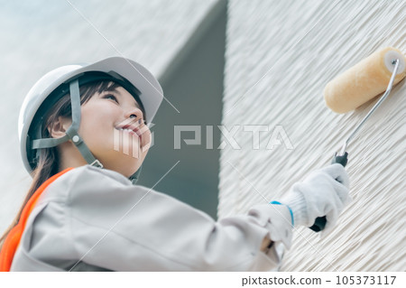 在外牆上塗塗層劑的年輕婦女 在外牆上塗塗層劑的年輕婦女 105373117