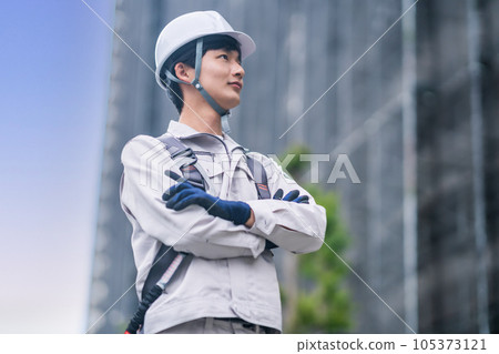 A young man wearing a helmet working at a construction site 105373121