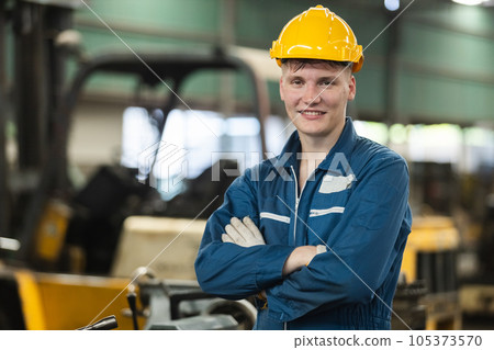 Man engineering wearing uniform safety and yellow hardhat standing at machine in factory industrial 105373570