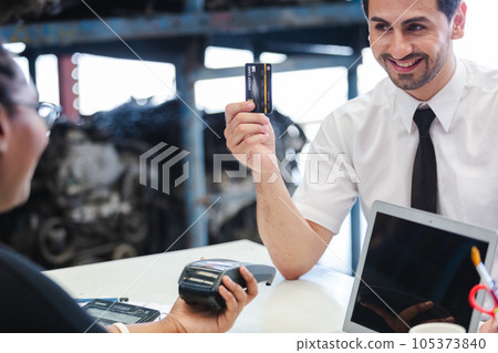 Male customers paying by credit card at counter in auto parts stores. business warehouse Male customers paying by credit card at counter in auto parts stores. business warehouse 105373840