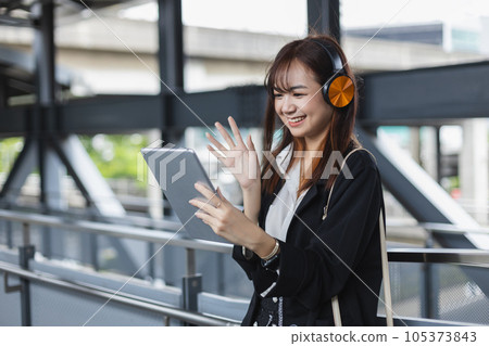 Asian beautiful female video conference calling on digital tablet wear headphones online app. Asian beautiful female video conference calling on digital tablet wear headphones online app. 105373843