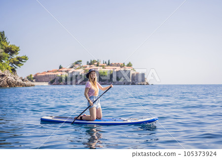 Young women Having Fun Stand Up Paddling in blue water sea near st stefan island in Montenegro. SUP 105373924