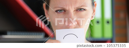 Unhappy woman in office holds paper with sad emotion in front of her mouth. 105375335